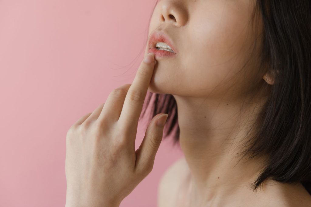 Mujer tocándose el labio inferior por una afta en la boca