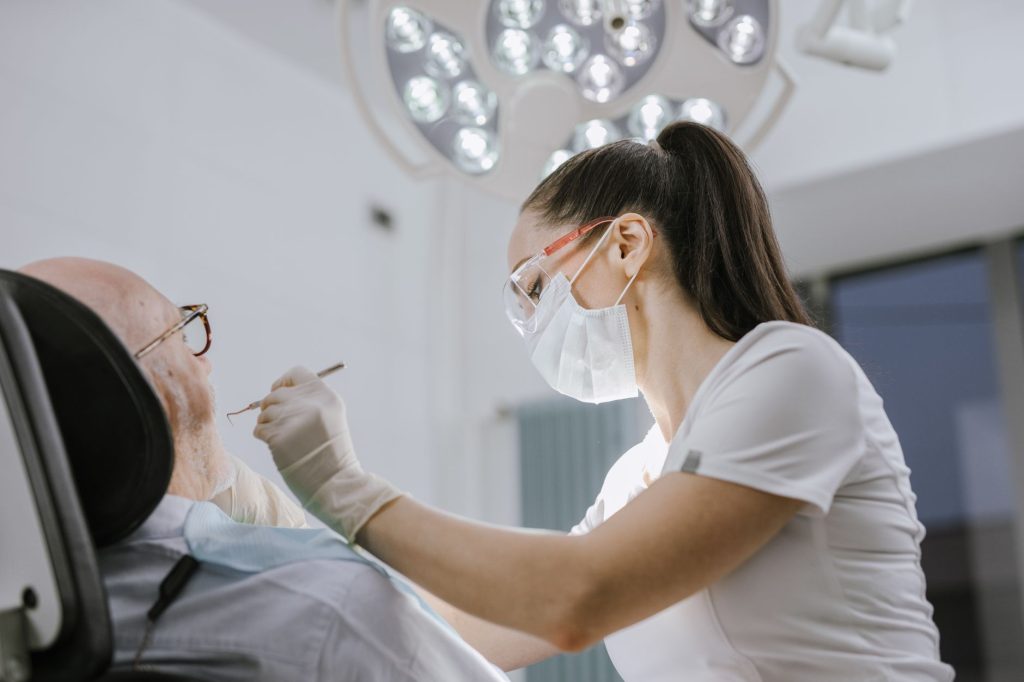 Dentista revisa la boca de una paciente mayor en la consulta dental.